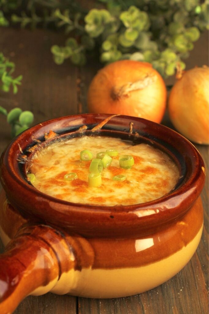 One-pot cheesy onion soup on a rustic wooden table.