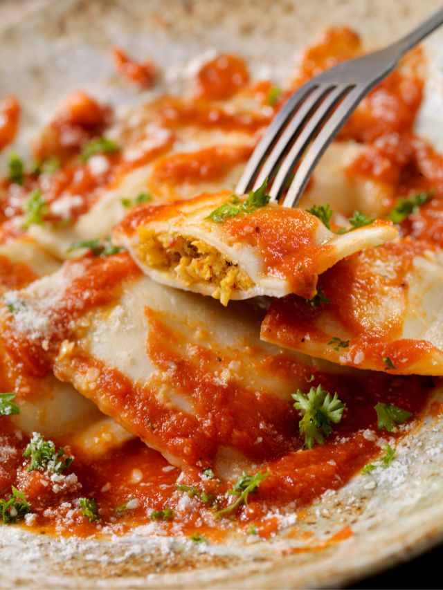 Lobster ravioli with tomato sauce served on a plate with a fork.