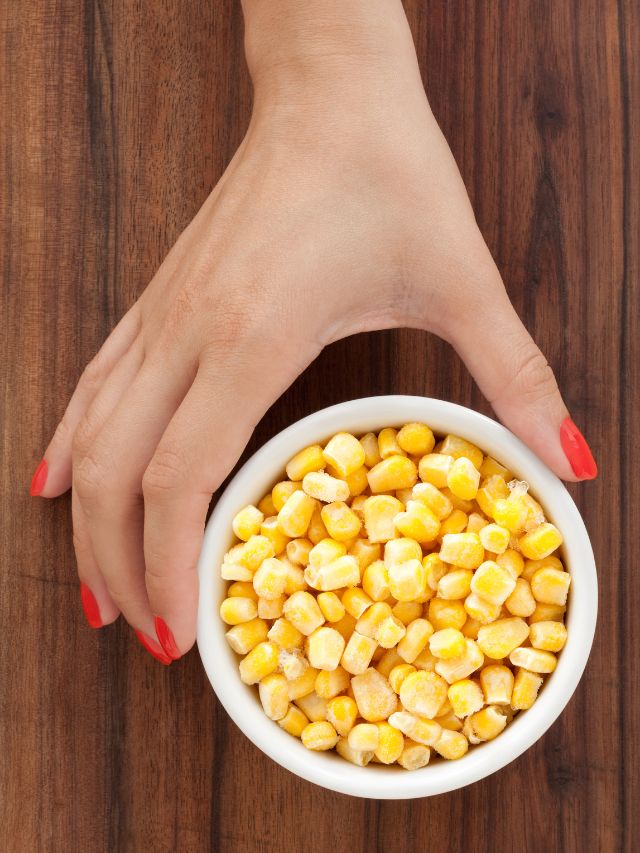 a cup of corn on wooden table with hand