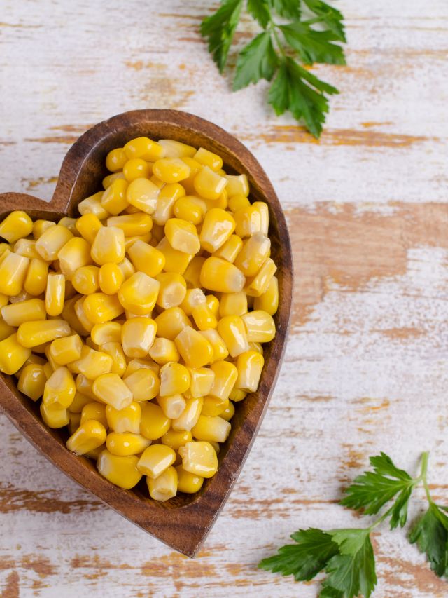 a heart shaped wooden bowl filled with corn