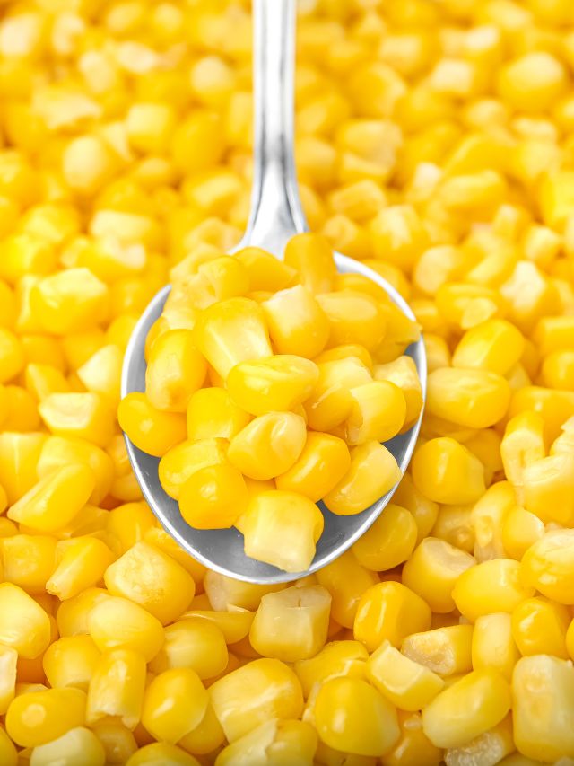 a spoonful of corn on top of a bunch of corn