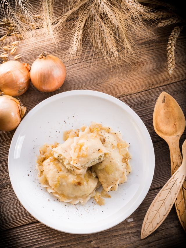 pierogies on plate with onion and wooden spoons