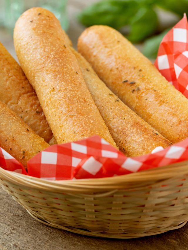 breadsticks in a basket with red checkered paper