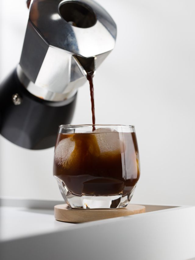 pouring cold brew into a glass with ice