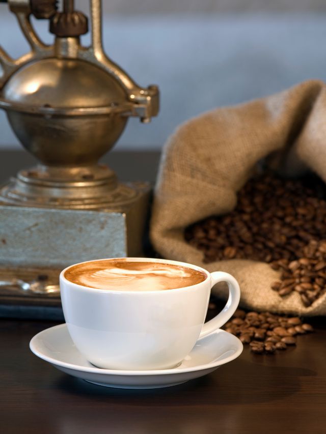cappuccino in a white coffee mug with coffee beans