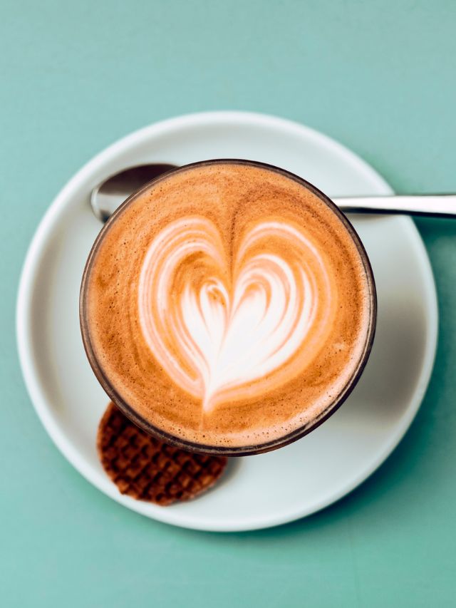 top view of a cappuccino in a glass with a spoon on a serving dish