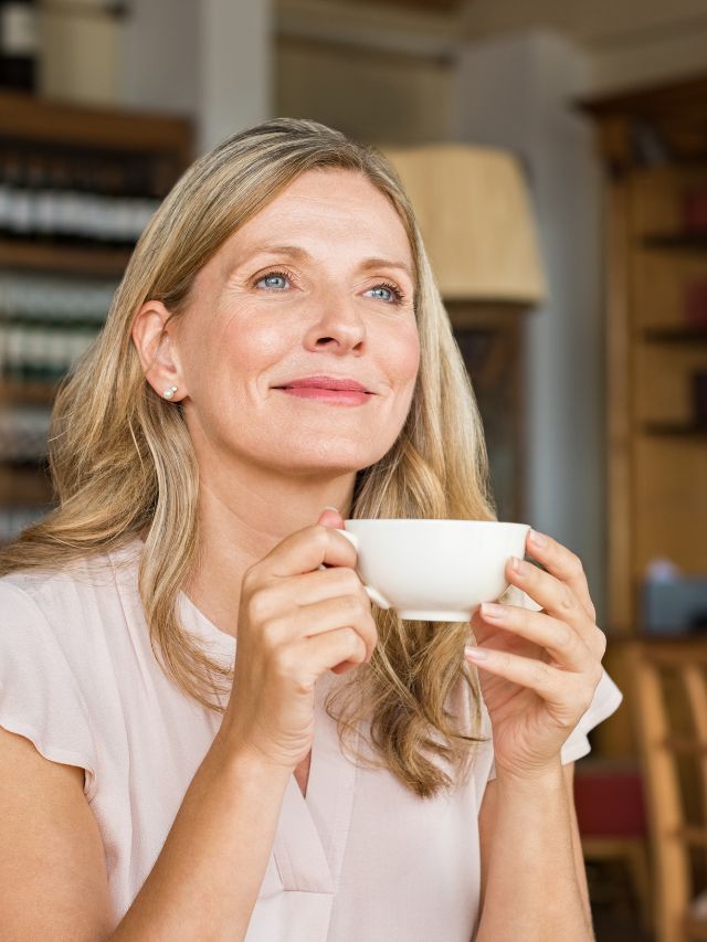 woman looking out holding her cup of coffee