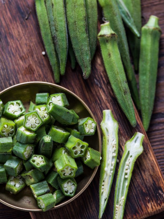 whole and cut up okra on a wooden table