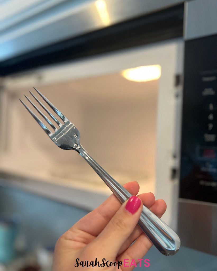 holding fork in front of microwave