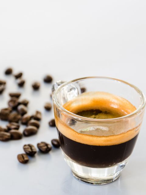 espresso shot in a glass and coffee beans