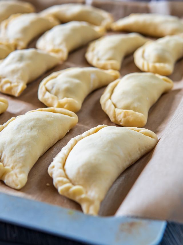 uncooked pasties on lined baking sheet