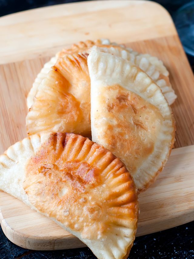 cooed pasties stack on top of one another on a wooden cutting board