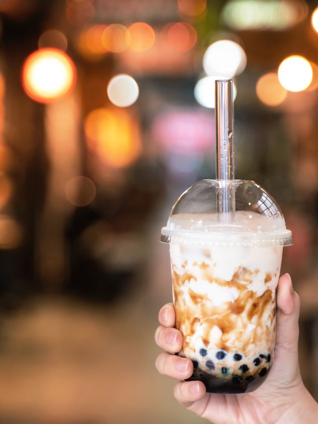 hand holding bubble tea in cup with a straw