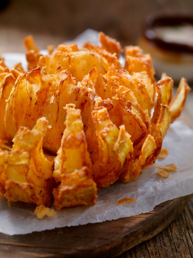 cooked blooming onion on wood cutting board