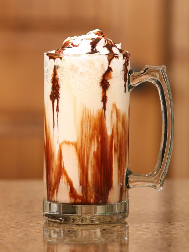 iced mocha coffee in a tall mug glass with chocolate syrup on top