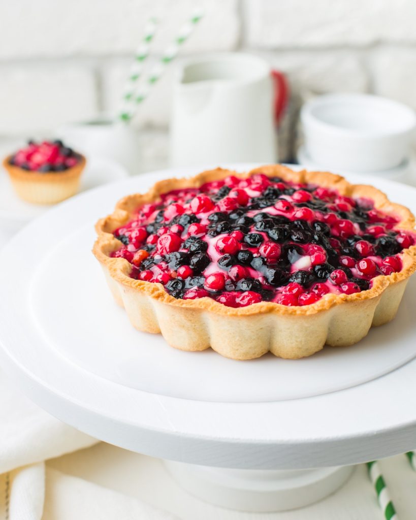 A tart with berries on top of a white plate.
