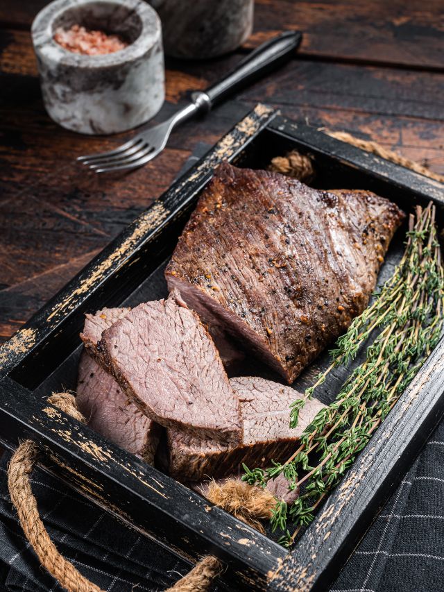 tri tip steak with garnish on a wooden plate
