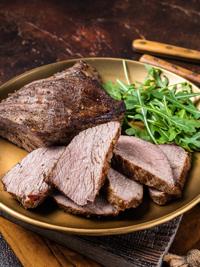 sliced meat on plate with leafy greens