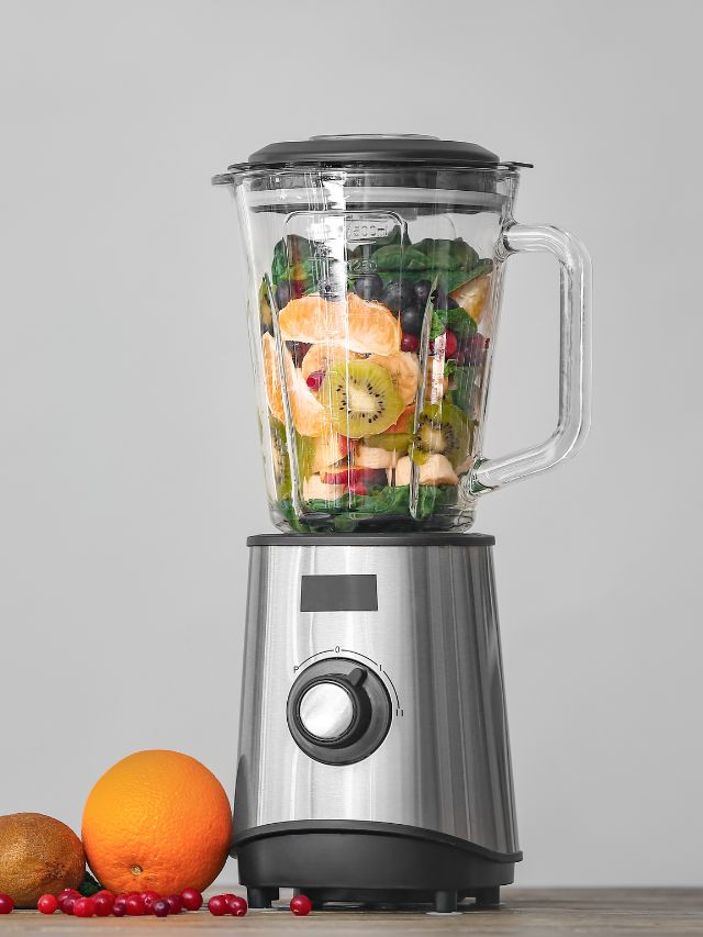 A blender full of fruit and vegetables on a table.