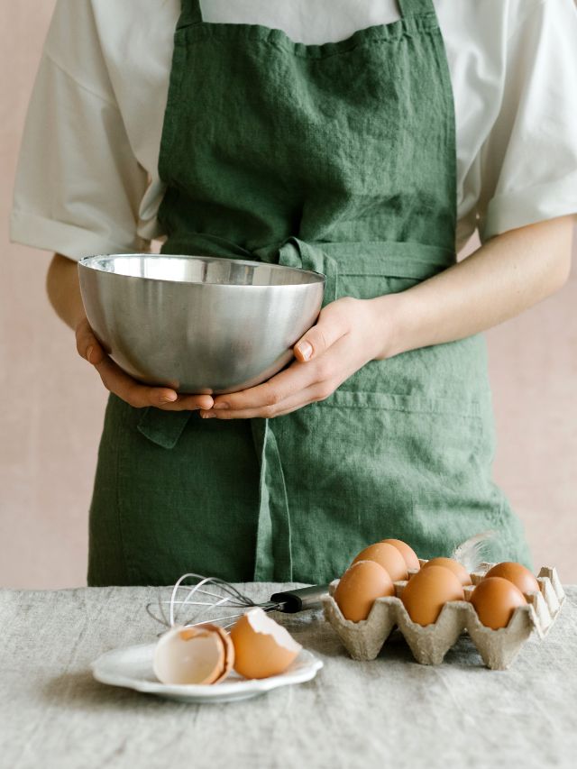 baker using eggs and stainless steel bowl