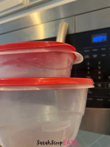 2 rubbermaid containers held in front of a microwave