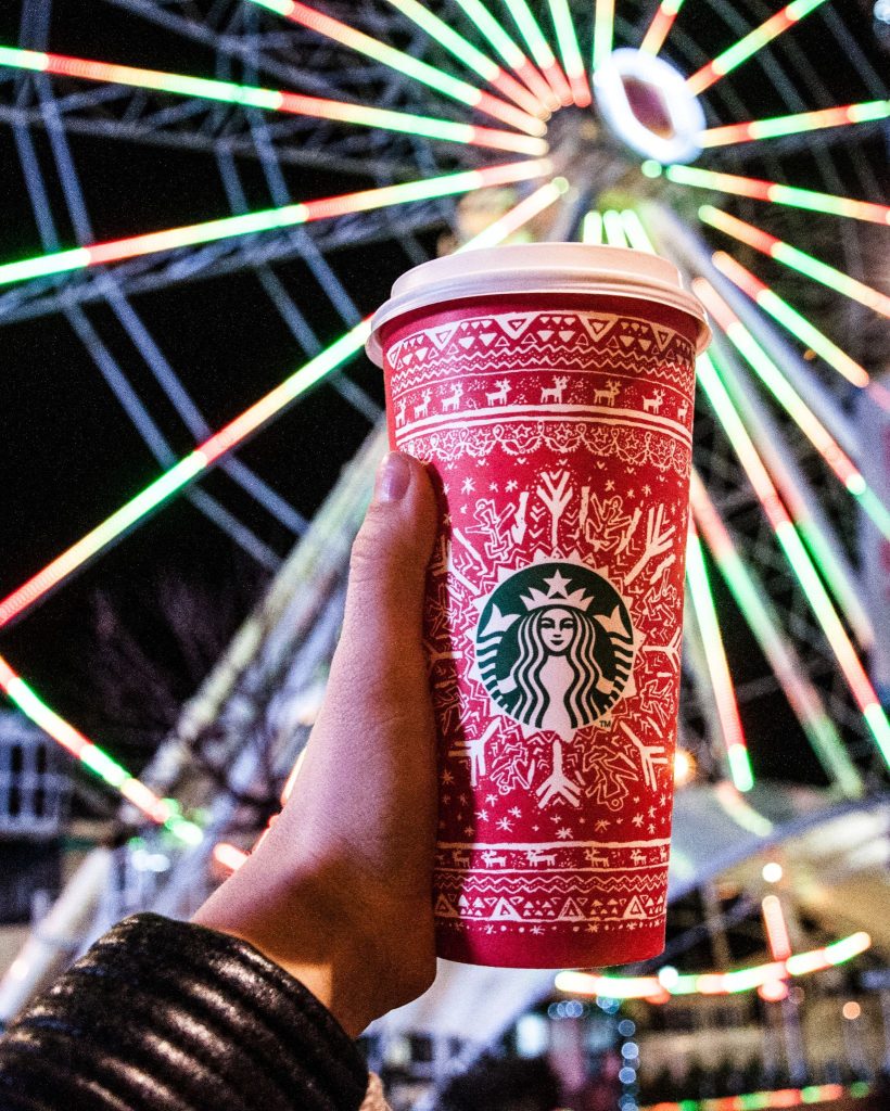 christmas starbucks cup with ferris wheel behind it