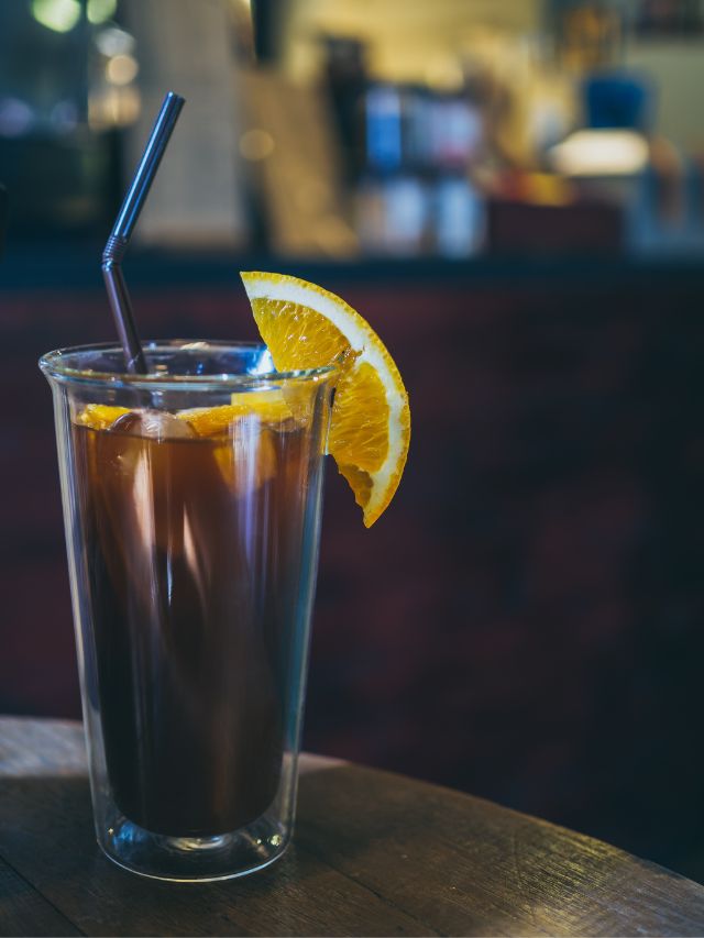 coffee romano in a glass with lemons and a straw