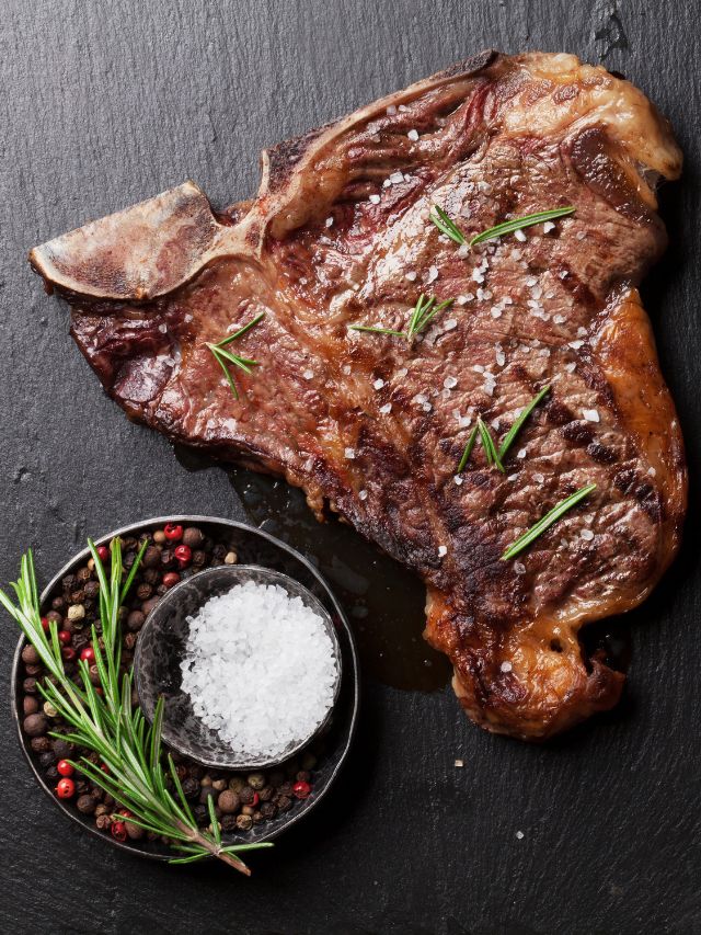 steak on black background with pepper and salt and garnish