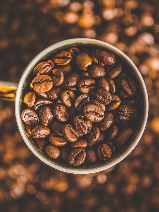 Coffee beans in a cup on a brown background.