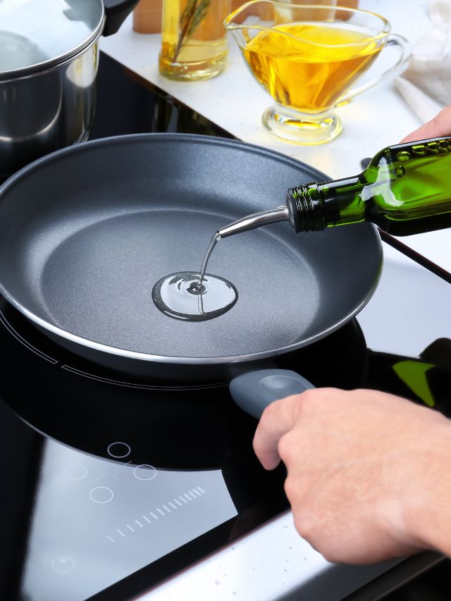 A person pouring oil into a frying pan.