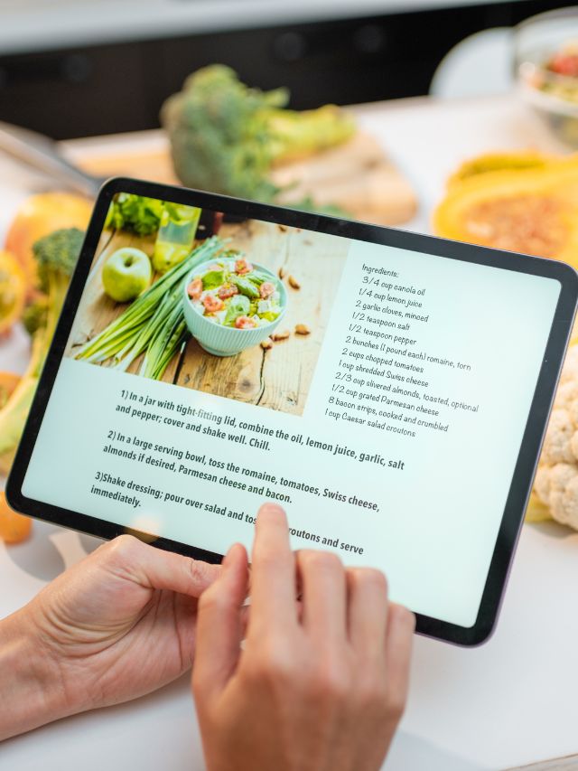 A woman is using an ipad to read a recipe.