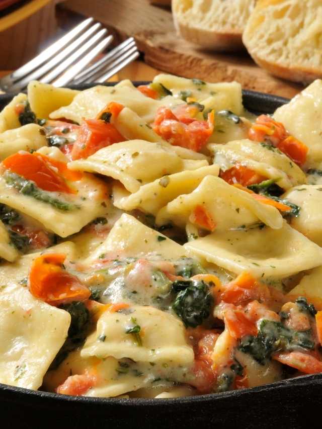 A skillet filled with ravioli and spinach.