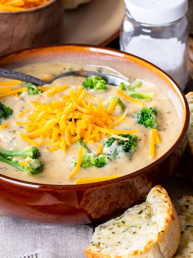 A bowl of broccoli soup with cheese and bread.