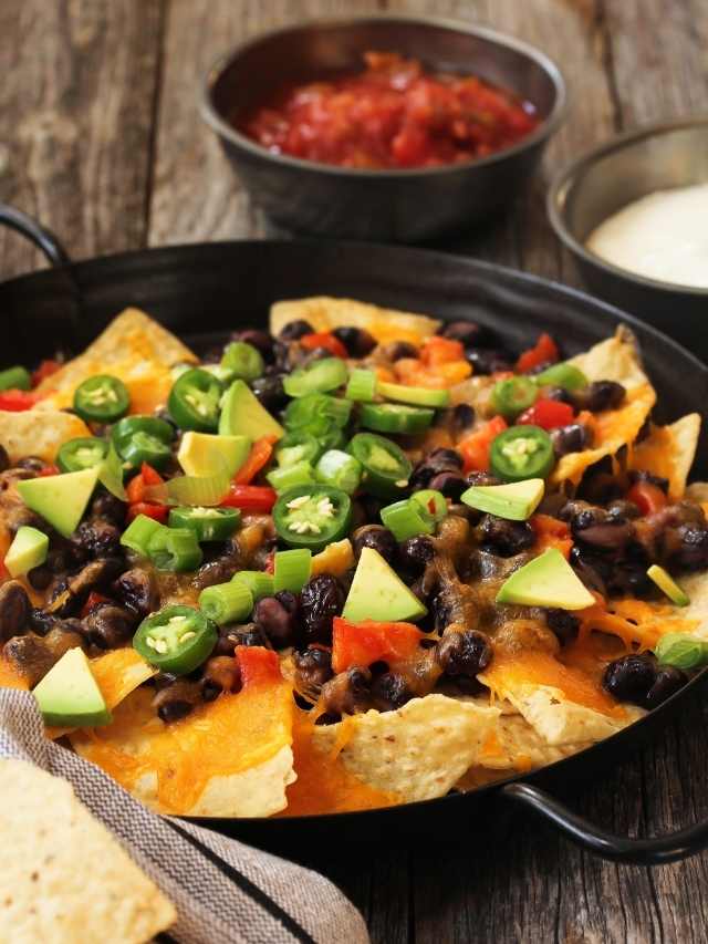 Nachos in a skillet with salsa and tortilla chips.