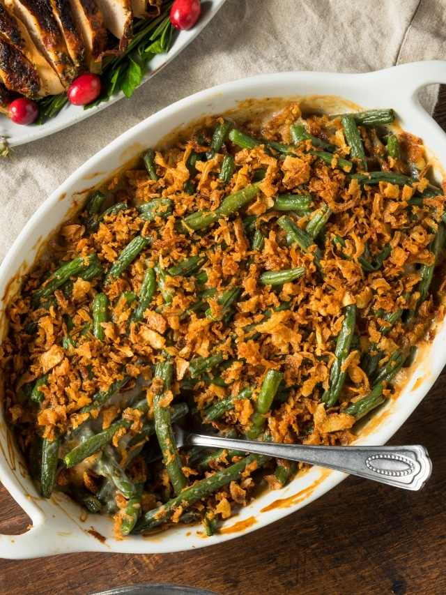 Green bean casserole in a white dish with a spoon.