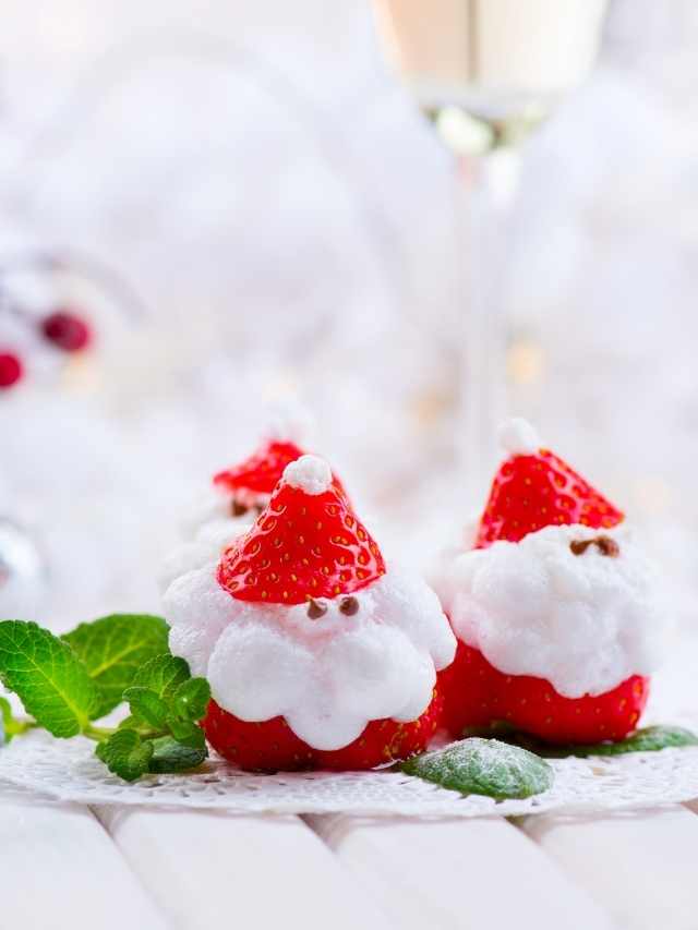 Strawberries with santa claus on a white plate with a glass of wine.