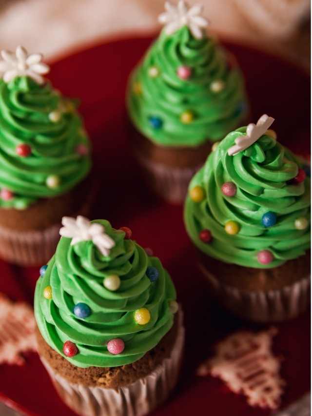 Three christmas tree cupcakes on a red plate.