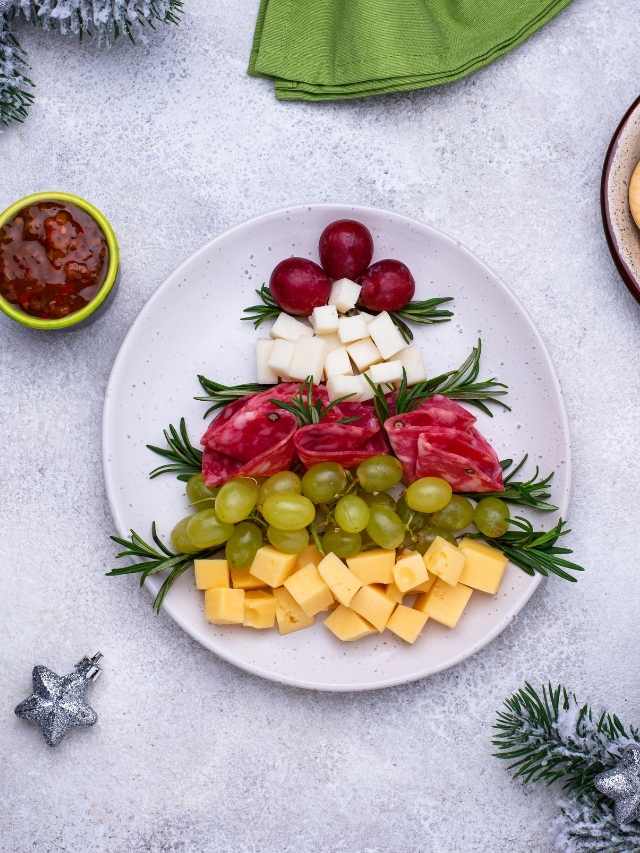 A plate with cheese, grapes and grapes in the shape of a christmas tree.