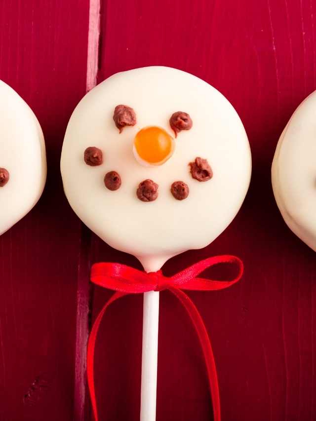 Three snowman shaped lollipops on a red background.