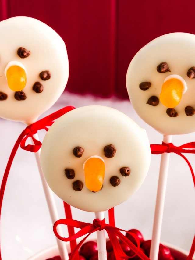 Three snowman shaped lollipops in a bowl.