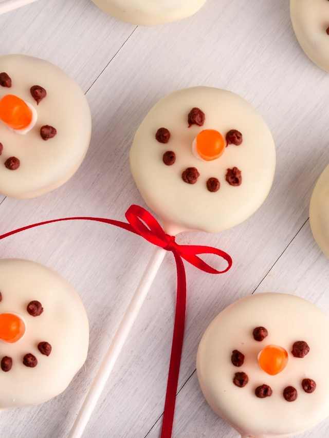 Snowman shaped lollipops on a white surface.