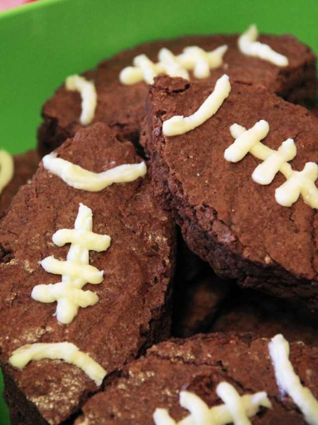 Chocolate football cookies in a green bowl.