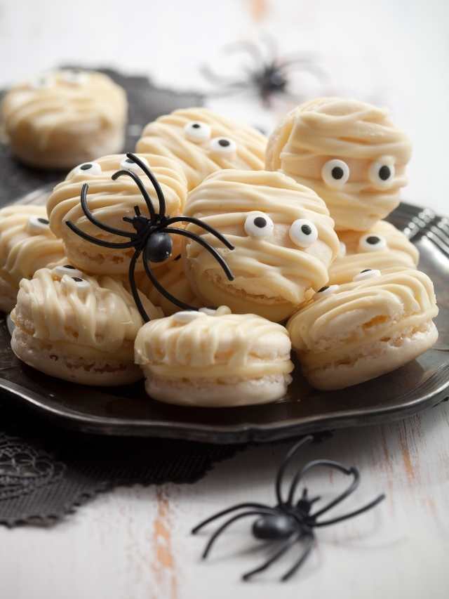 Mummy macarons on a plate with spiders and eyes.