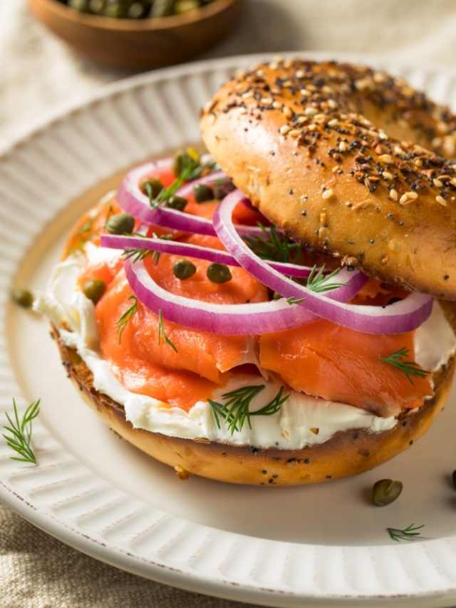 A bagel with salmon, onions and pickles.