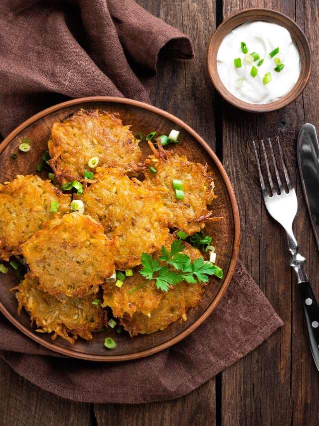 Potato pancakes on a plate with sour cream and parsley.