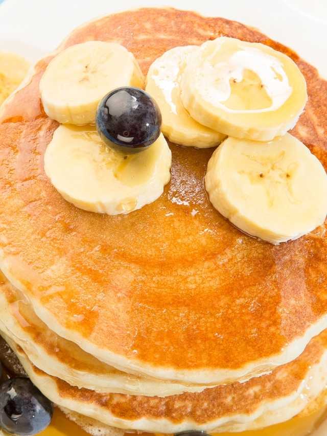 A stack of pancakes with blueberries and bananas.