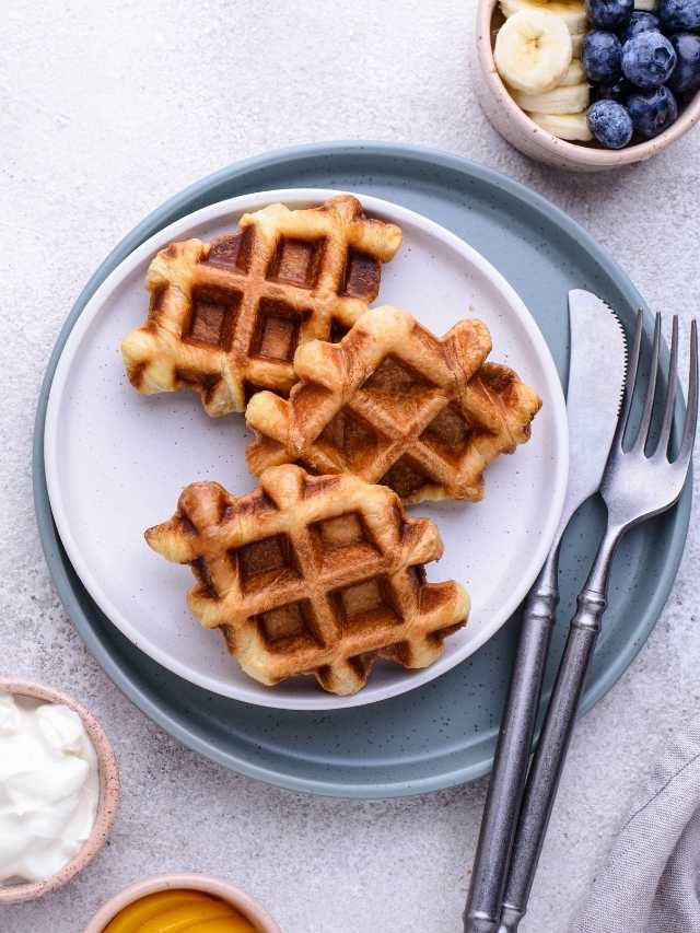 Waffles on a plate with blueberries and yogurt.