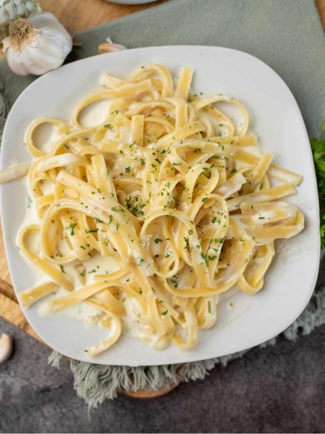 Fettuccine with parmesan cheese and garlic on a white plate.