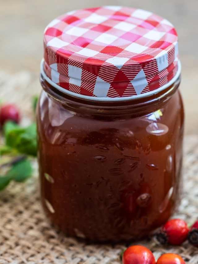 A jar of cranberry jam with a red checkered lid.