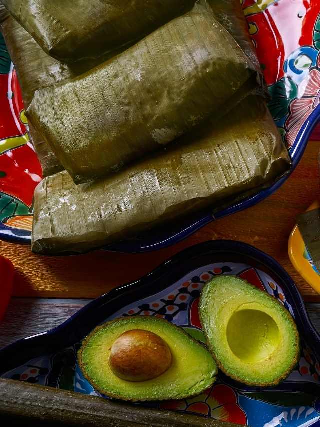 A plate of tamales, guacamole, and avocado.